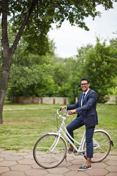 Young businessman sitting on bicycle and looking at camera