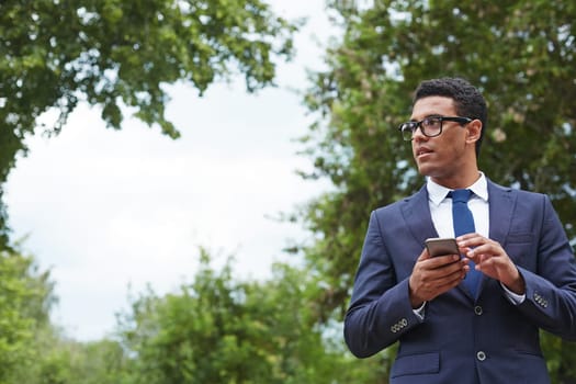 Young businessman with cellphone working in park