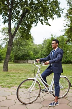 Confident businessman sitting on bicycle in natural environment