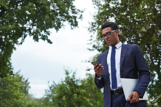 Handsome businessman with digital tablet using cellphone in natural environment