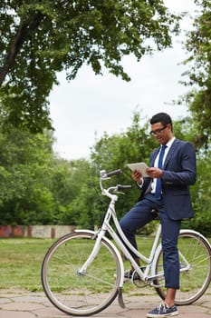 Young businessman sitting on bicycle and networking in park