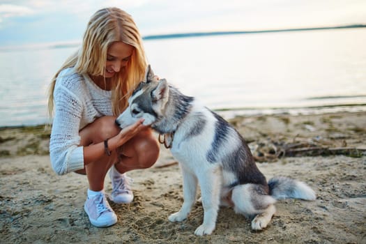 Blond girl petting her dog by the seaside