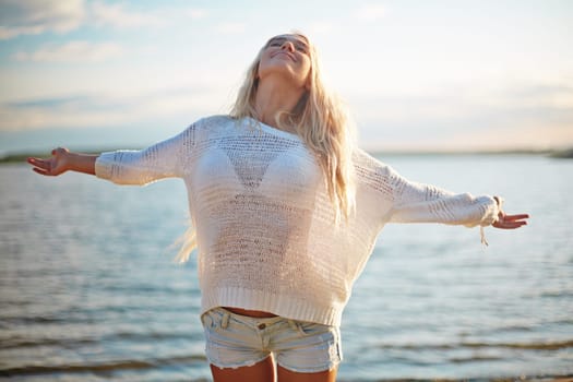 Delighted blond girl in white pullover and denim shorts enjoying her summer vacation by the sea