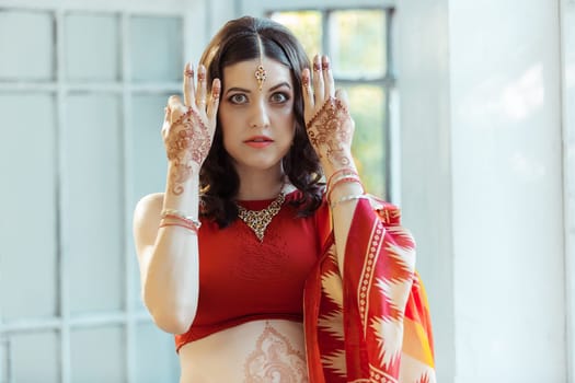 Indian picture on woman hands and belly, mehendi tradition decoration, resistant design by brown henna on white room background