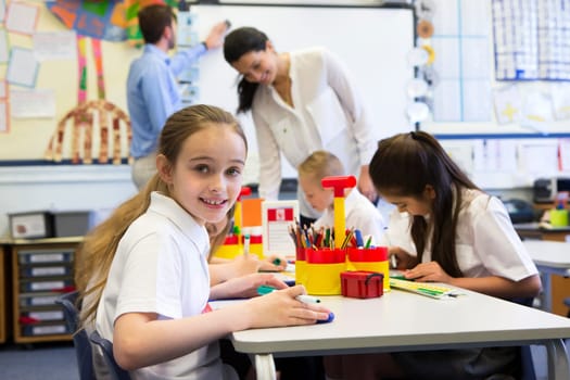 Portrait of a cute young schoolgirl smiling at the camera while sitting at her desk.