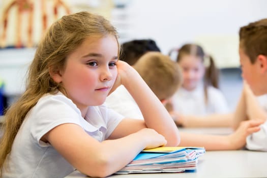 A close up shot of a little girl at school who looks distant and upset.