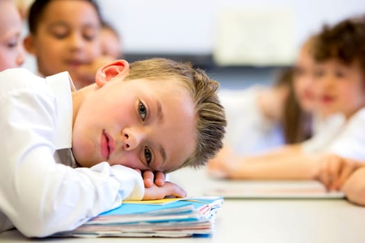 A close up shot of a little boy at school who looks distant and upset.