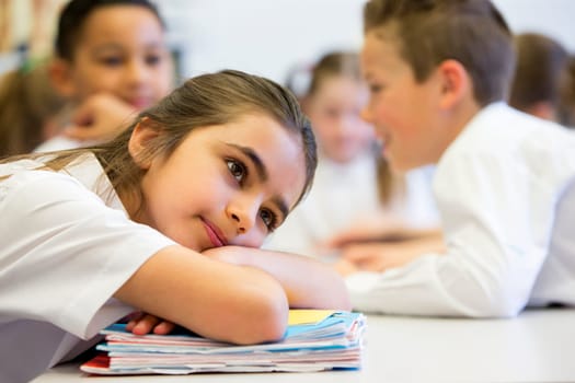 A close up shot of a little girl at school who looks distant and upset.