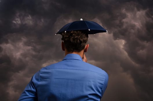 Business man with small umbrella in front of a heavy storm