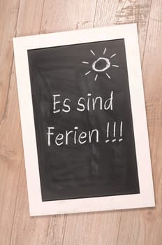 Chalkboard with the German word vacation on a rustic wooden background