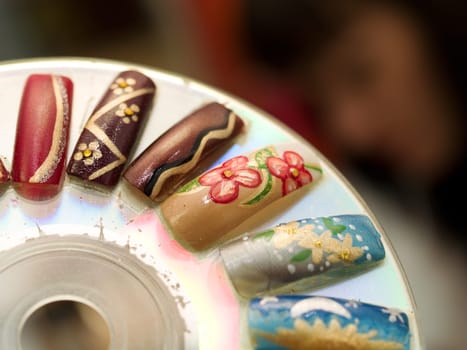 Artificial fingernails and female manicurist in the background.