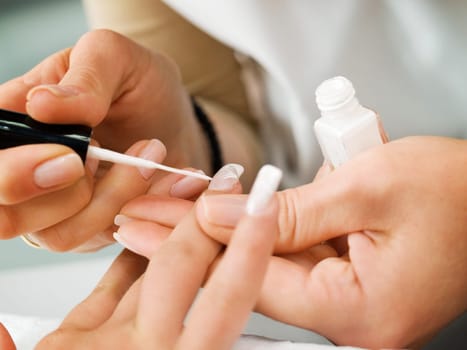 Girl fingernails being manicured.