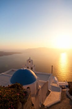 Famous church in Fira, Santorini at sunset with a perfect view of the volcano