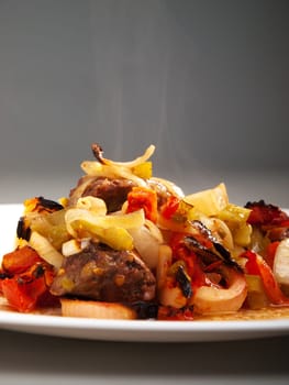 Beef stew with green peppers, onion and tomatoes, served in a plate, steaming