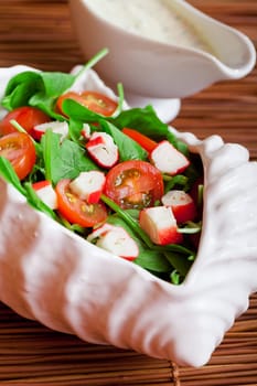 Mediterranean seafood salad with spinach leaves, cherry tomatos and surimi and mayonnaise sauce
