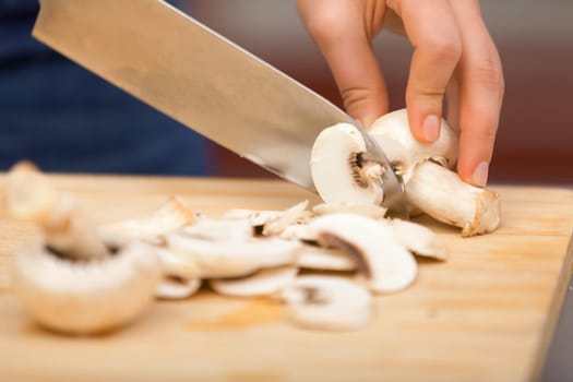 Young woman cutting mushrooms for cooking with knife