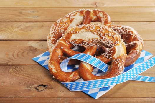 Three original Bavarian lye pretzels with salt on wooden floor