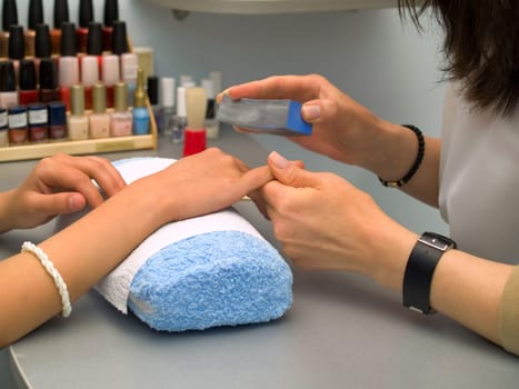 Girl fingernails being manicured.