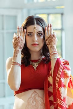 Indian picture on woman hands and belly, mehendi tradition decoration, resistant design by brown henna on white room background
