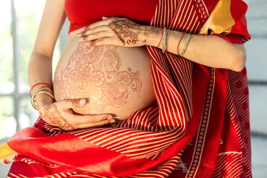Indian picture on woman hands and pregnant belly with henna tattoo  on white room background