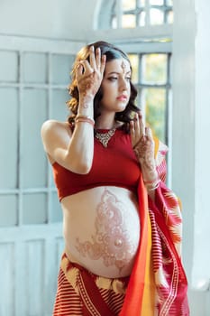 Indian picture on woman hands and pregnant belly with henna tattoo  on white room background