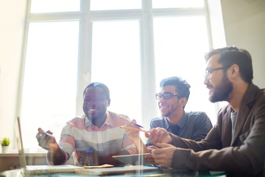 Group of employees pointing at laptop display while discussing project