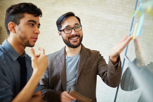 Asian businessman pointing at reminder while explaining his viewpoint to colleague