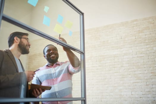 African businessman pointing at reminder with his colleague near by