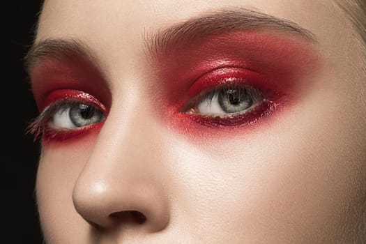 Beautiful young female face with bright fashion red make-up. The gray eyes and nose close up