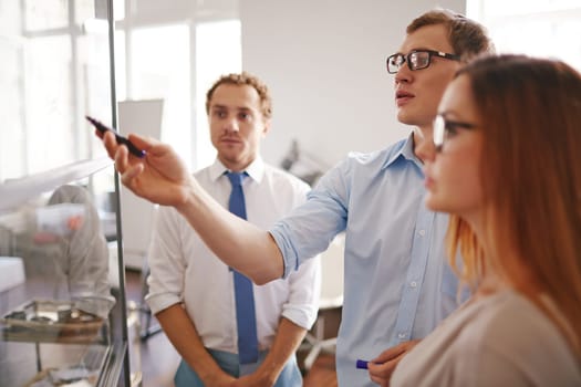 Confident businessman pointing at information on board with his colleagues near by