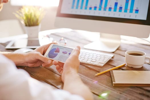 Businessman with cellphone looking at diagram with financial data