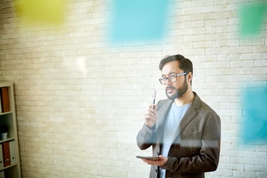 Handsome businessman with notepad planning work in office