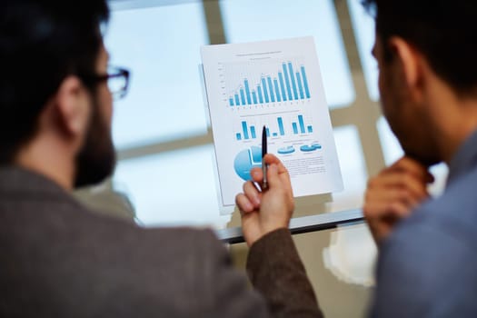 Businessman explaining chart in document to colleague