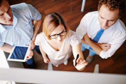 Confident businesswoman with highlighter pointing at board with two male colleagues near by