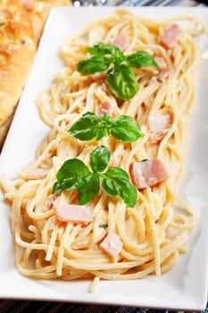 Spaghetti carbonara decorated with fresh basil leaves