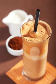 Frappe coffee in a glass - mixed instant coffee with water, milk and ice cubes