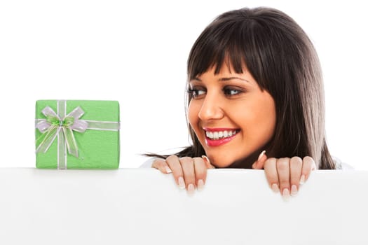 Young woman with a christmas gift behind white billboard