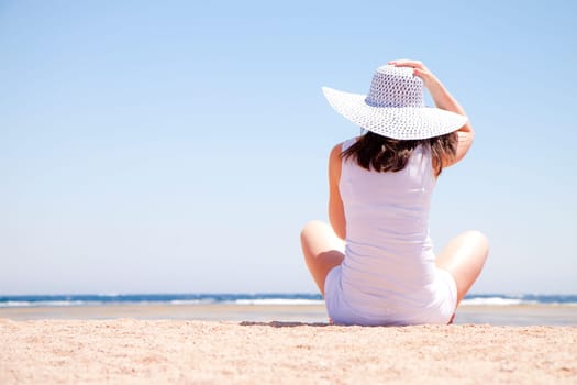 young woman sitting on the sand at the beach
