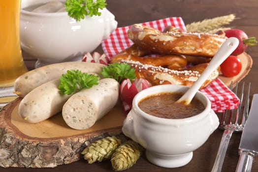 White sausage breakfast with sausages,pretzels,white beer and sweet mustard on wood substrate