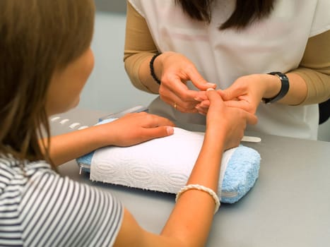 Girl fingernails being manicured.