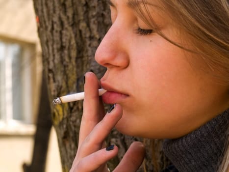 Young student smoking in front of her school