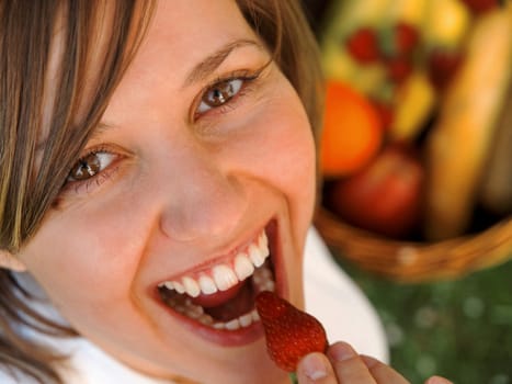 Woman eating strawberry outdoors