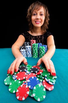 Young woman holding gambling chips on black background