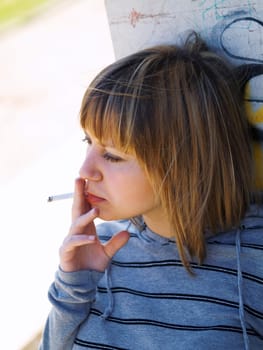 Young student smoking in front of her school