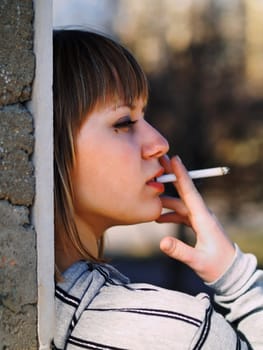 Young student smoking in front of her school