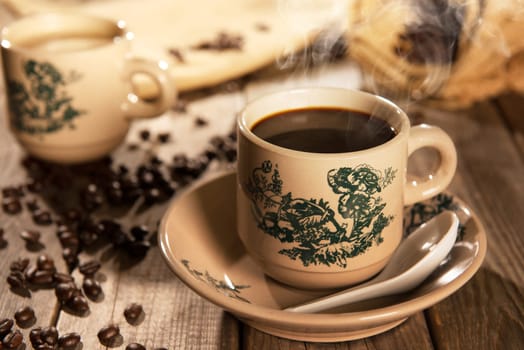 Steaming traditional Chinese nan yang style coffee in vintage mug and saucer with coffee beans. Fractal on the cup is generic print. Soft focus setting with dramatic ambient light on dark wooden background.