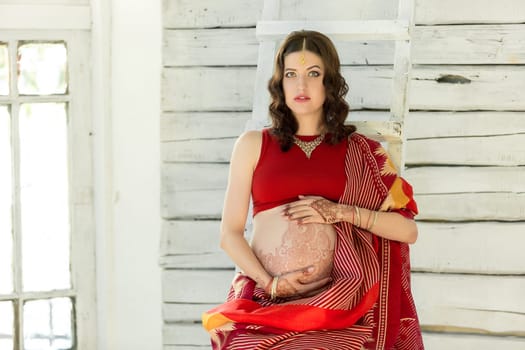 Indian picture on woman hands and pregnant belly with henna tattoo  on white room background