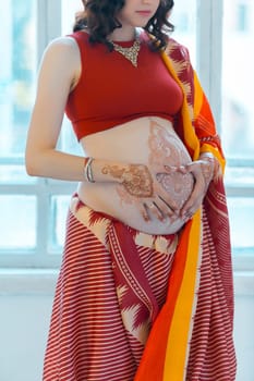 Indian picture on woman hands and pregnant belly with henna tattoo  on white room background