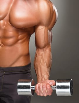 Closeup of a handsome power athletic man bodybuilder doing exercises with dumbbell. Fitness muscular body on dark background.