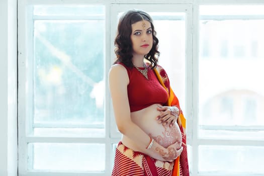 Indian picture on woman hands and pregnant belly with henna tattoo  on white room background